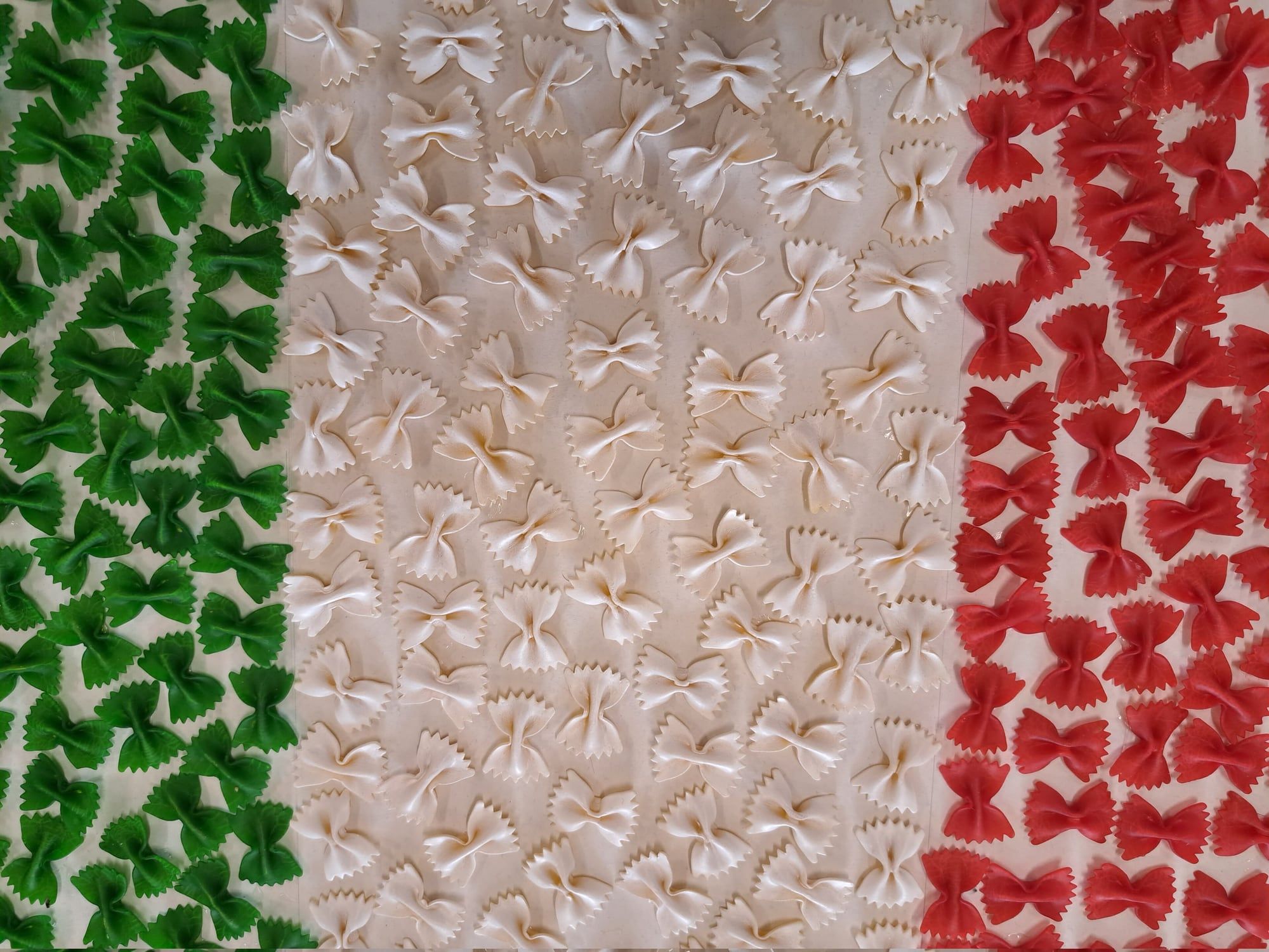 Fresh handmade pasta in the green, white and red colours of Italy laid out on a wooden board