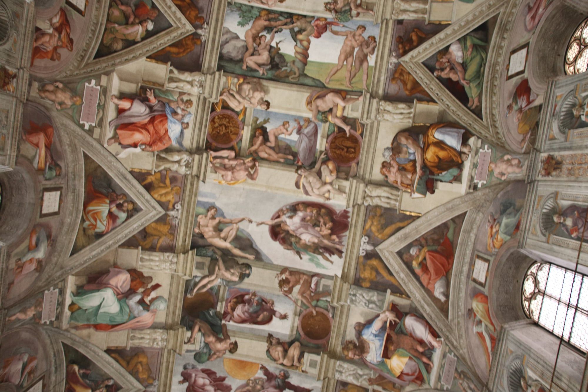 The frescoed ceiling of the Sistine Chapel with Michelangelo's Creation of Adam at the centre