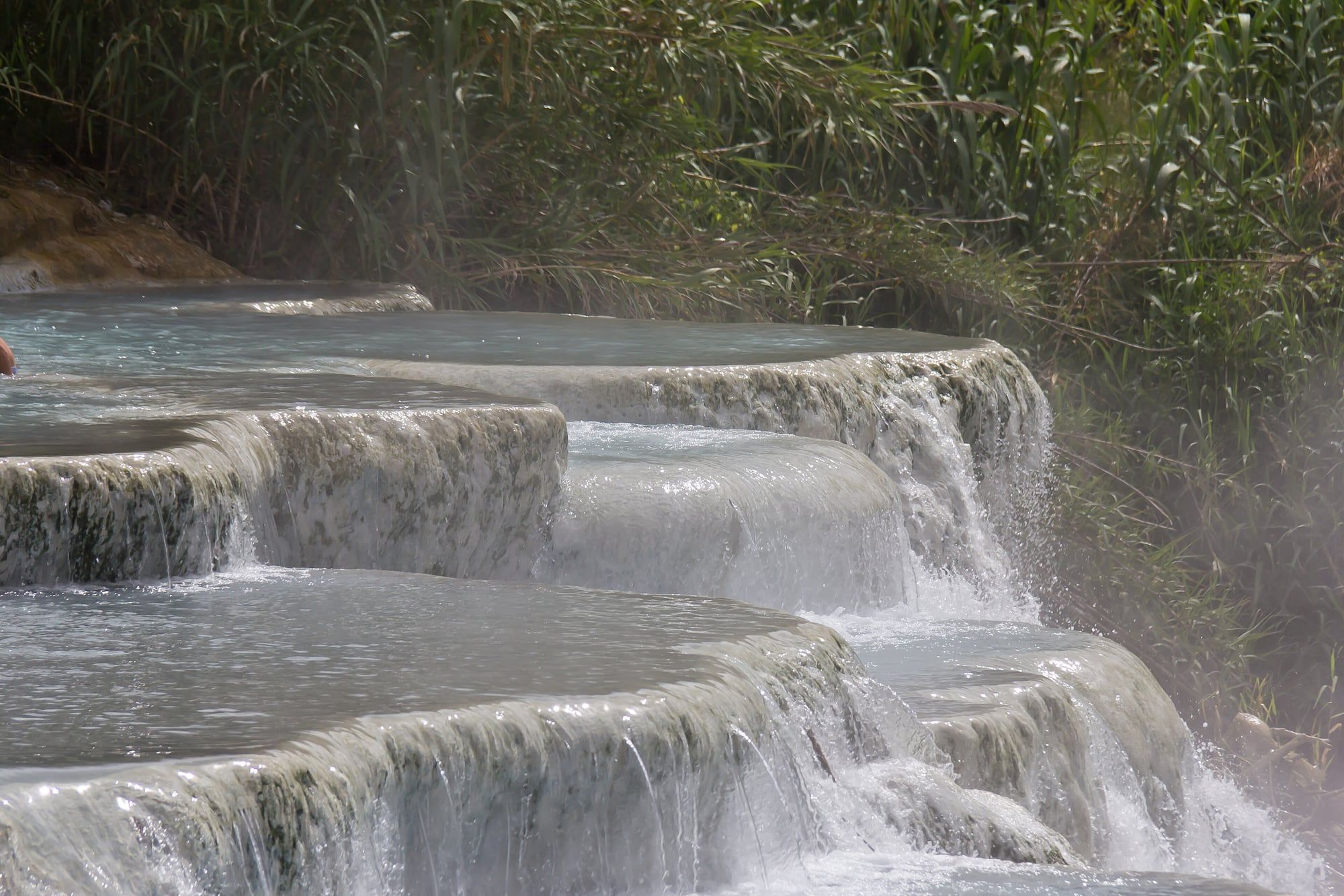 Bagnanti nelle vasche termali turchesi delle Cascate del Mulino alle Terme di Saturnia